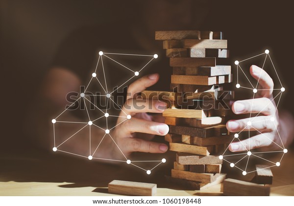 organization ideas concept with\
hand pull out block of wooden piece from stack strategy and risk\
concept