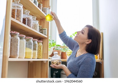 Organization Of Pantry, Woman In Kitchen Near Wooden Rack With Cans And Containers Of Food