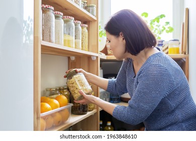 Organization Of Pantry, Woman In Kitchen Near Wooden Rack With Cans And Containers Of Food