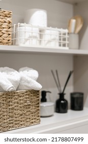 Organization Of Space In The Bathroom Cabinet. Selective Focus On Rolled Fresh Washed Towels In Wicker Box In Modern Open Shelf Case. Toiletries In White Closet Or Cupboard. Tidying Up At Home Concept