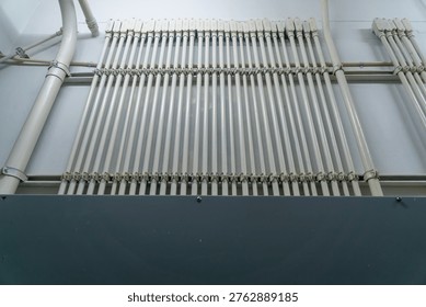 An organized array of pipes and tubes mounted on a wall, showcasing a modern industrial design. The clean lines and geometric arrangement highlight efficiency and functionality.