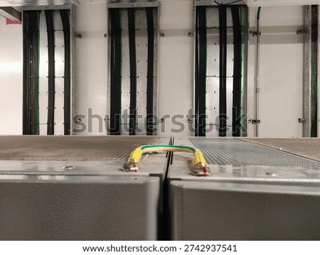 Organized electrical cable management system with conduits and green earth wires installed on a white wall.