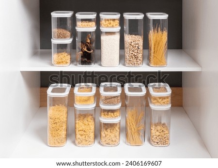 Organized Kitchen Cabinet with Multiple Stackable Clear Containers Displaying a Italian Pastas, Cooking Ingredients, and Diverse Legumes, Arranged on White Shelves for Optimal Kitchen Order.