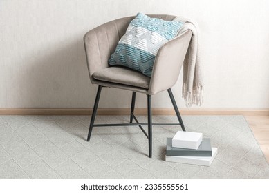An organized and modern interior featuring a white-painted wall, wooden floor, and a single accent chair with a green cushion and books and the floor