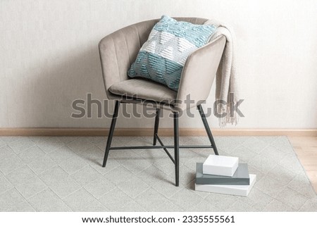 An organized and modern interior featuring a white-painted wall, wooden floor, and a single accent chair with a green cushion and books and the floor