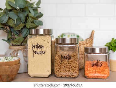 Organized Pantry Staples In Labeled Glass Jars In A Light And Bright Kitchen
