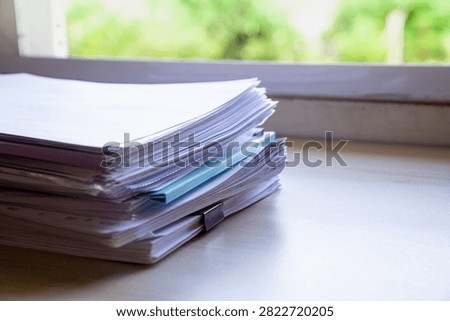 Organized Paper Files and Document Stack on Desk by Window