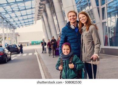 Organized And Ready To Go. Cropped Shot Of Happy Family Standing Outdoor Near Entrance Of Airport And Waiting For Taxi Arrival