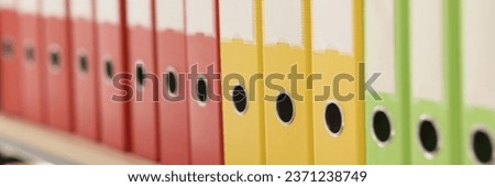 Organized ring binder structure and archive with information. Multi-colored folders with accounting materials put in row on shelf in office closeup
