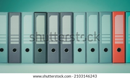 Organized ring binders on a shelf, one is highlighted, archive and storage concept