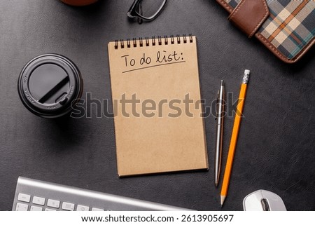 Organized work desk setup with PC, office supplies, coffee and a notepad for writing a to-do list. Top view with clean, productive layout