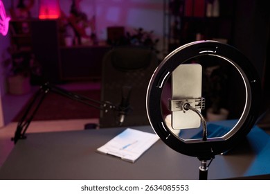 Organized workspace setup including ring light, microphone, smartphone, notes on desk suitable for podcasting or streaming with creative ambiance enhancing atmosphere