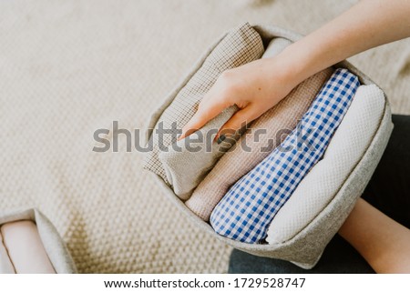 Organizing and folding clothes in boxes and baskets. Concept of tidiness, minimalism lifestyle and japanese t-shirt folding system. Wardrobe storage system