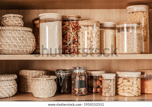 Organizing zero waste storage\
in kitchen. Pasta and cereals in reusable glass containers in\
kitchen shelf