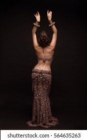 Oriental beauty with a slender figure and a narrow waist. View from the back . Hands raised up.