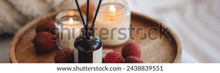 Oriental interior, Bali, Thai vibes banner. Sweet home perfume with tropical exotic fruits. Reed diffuser on wooden tray in a bedroom. Burning candles, atmosphere of relaxation, detention, meditation