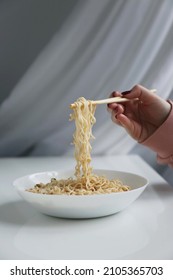 Oriental Noodles In A Plate And Chopsticks In Hand