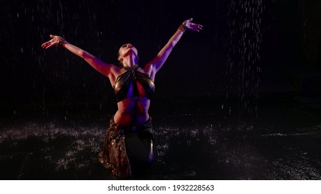 oriental priestess is dancing traditional dance under rain, sexy woman is dancing exotic dance