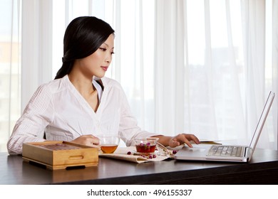 Oriental tea and young woman using a laptop computer