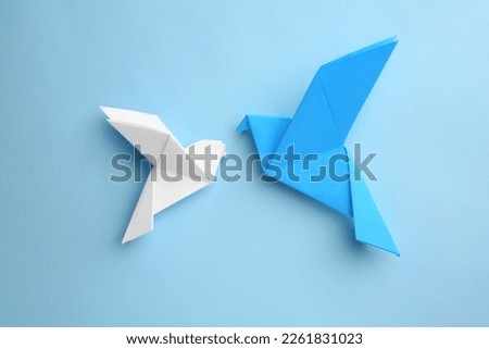 Origami art. Colorful handmade paper birds on light blue background, flat lay