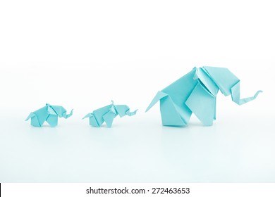 Origami blue elephant family on white background.Mum leading the childs