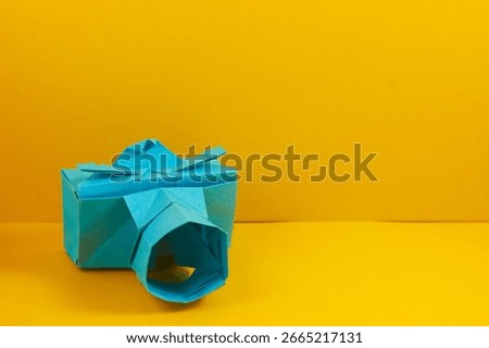 Origami camera with yellow background.