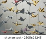 Origami from colored paper. Cranes with which you can decorate the premises for a solemn event. Colored paper cranes symbolize peace.