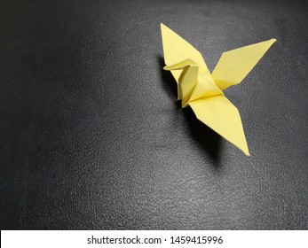 Origami Crane On Dark Background. Yellow origami paper crane on 
black background with copy space. Paper bird on the table. - Shutterstock ID 1459415996