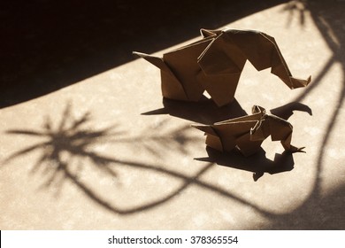Origami elephant family made of craft paper on a beautiful shadow scene.