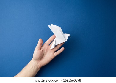 Origami pigeon  in human hands on a blue isolated background. World Peace Day concept. Close up studio photo. - Powered by Shutterstock