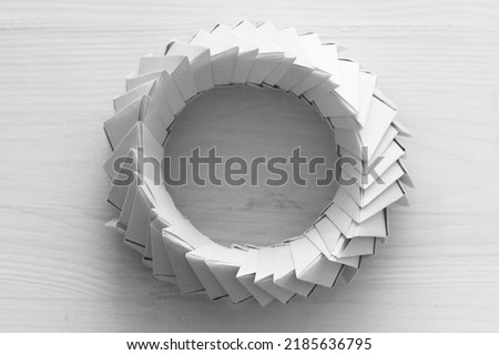 Origami ring. Abstract parametric object made of linked paper sheets lays on white table, top view