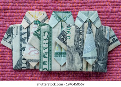 Origami shirt made of dollar banknote on red fabric background. Close up. Dollar bill T-shirt
