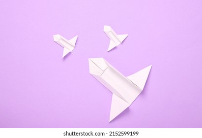 Origami space rockets shuttles on violet pastel background. Minimalism. Top view