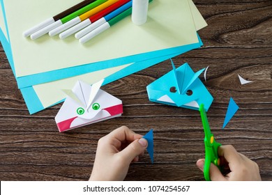 Origami toy made from paper angry bird. Children's art project craft for kids. Craft for children. Instruction for execution. Step 11. The child cuts out the details of the application.