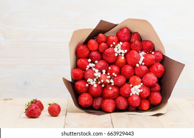  the original bouquet of strawberries with little white flowers on wooden table, light background