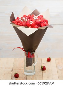 the original bouquet of strawberries with little white flowers in crystal glass, wood background