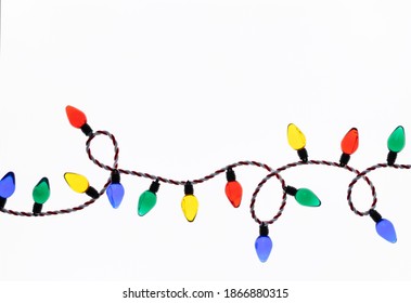 Original Christmas photograph of a string of colorful retro style Christmas tree lights looped across a bright white background