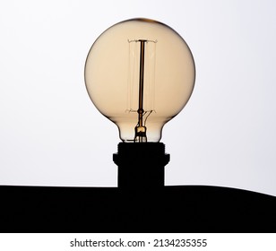 Original Circular Light Bulb Turned Off On White Background In Art Studio Photo 