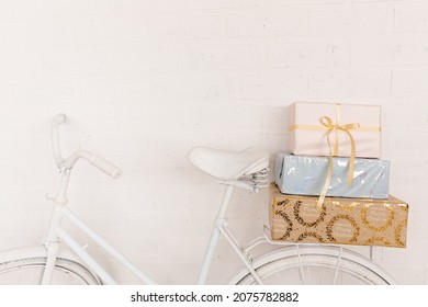 Original festive decor. White bicycle stands against background of white brick wall in back seat is pile of gift boxes. Wrapped in gift paper, tied with ribbons. Copy space. photo
