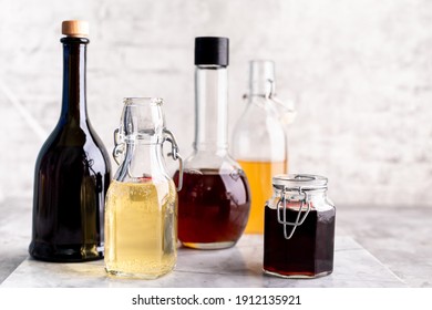 Original glass bottles with different vinegar on a marble table against a background of a white brick wall. Copy space. Horizontal. - Powered by Shutterstock