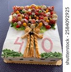 An original meat birthday cake to celebrate a 40th birthday. On top is a beautiful bouquet of meat and cheese products.