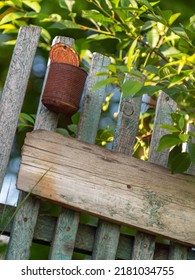 Original Mockup Of A Rustic Old Wooden Fence With Peeling Paint With Copy-space. An Empty Rusty Tin Can Imitating A Mailbox. Dunshifting And Hermitage Concept. Close-up With Selective Focus