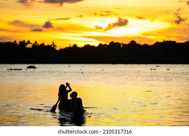 Orinoco, Venezuela - 11-23-2021:Family Of Native Indigenous Orinoco Tribe Swimming In Traditional Wooden Canoe