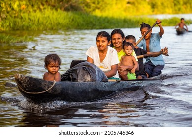 Orinoco, Venezuela - 11-23-2021:Family Of Native Indigenous Orinoco Tribe Swimming In Traditional Wooden Canoe