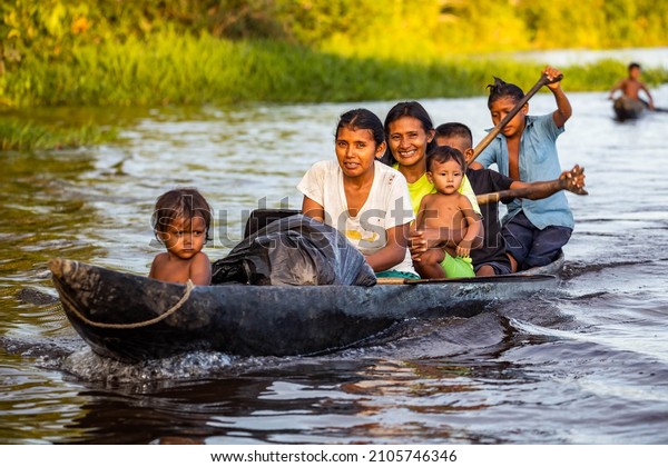 Orinoco, Venezuela -\
11-23-2021:Family of native indigenous Orinoco tribe swimming in\
traditional wooden\
canoe