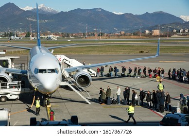 Orio Al Serio, Lombardy, Italy - December 26, 2019 : Passengers In Line To Get Onboard Jet Aircraft In The Airport On Sunny Day, Viewed From Terminal Window