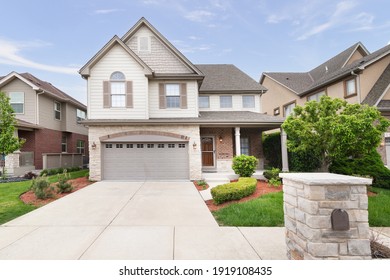 ORLAND PARK, IL, USA - MAY 20, 2019: A New Suburban House With Half Light Brown Siding And Have Brick And Stone, Brown Window Shutters, And A Front Porch.