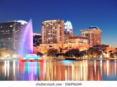 Orlando downtown skyline panorama over Lake Eola at night with urban skyscrapers, fountain and clear sky.