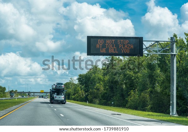 Orlando FL USA\
05/32/2020 electronic sign on the Florida Turnpike signaling not to\
stop, new covid bill by\
plate
