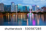 Orlando, Florida city skyline and water fountain at night in Lake Eola Park, building logos blurred for commercial use